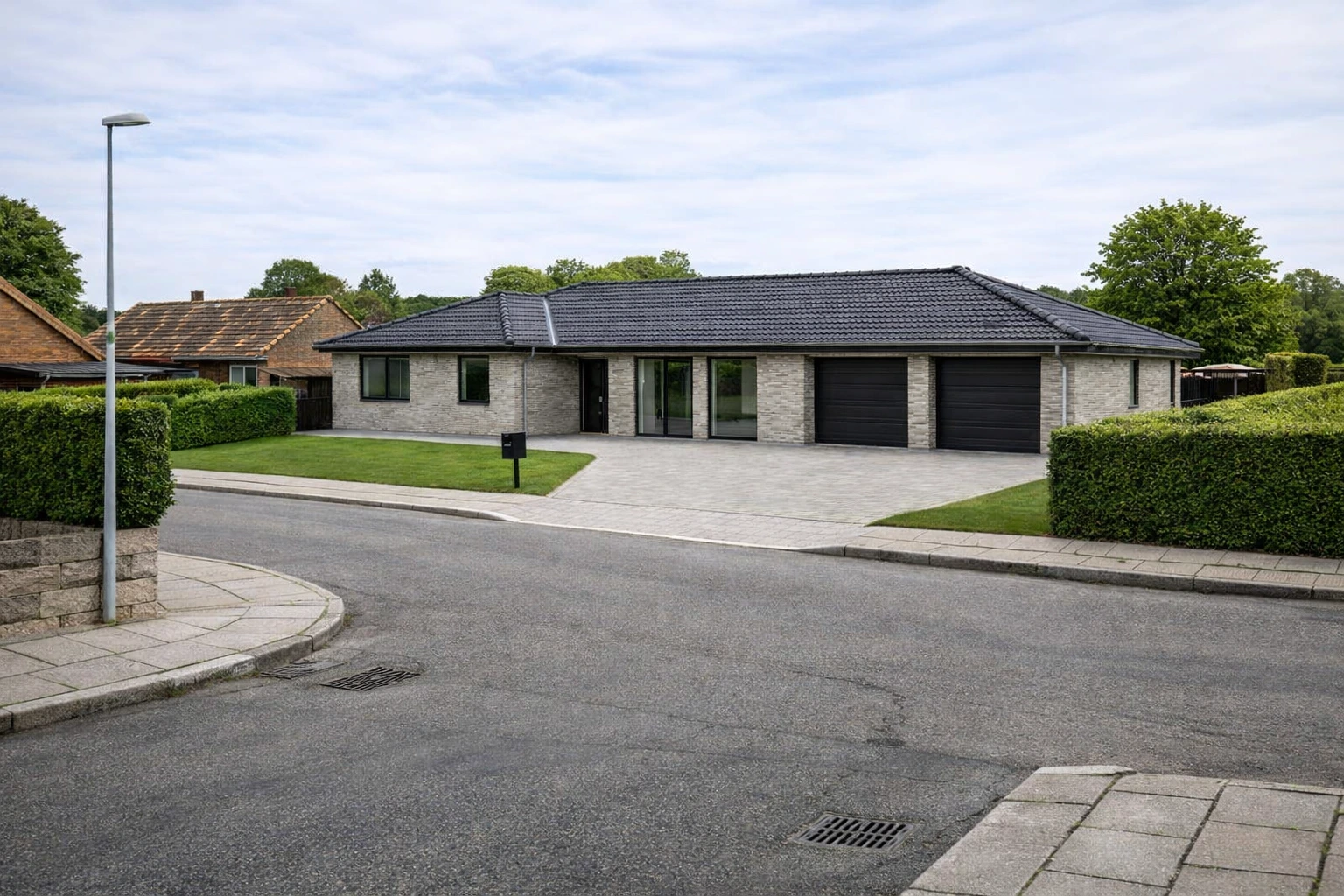 Nybygget étplansvilla i mursten i dansk villakvarter ved en ældre villavej – illustrerer valget mellem nedrivning og nybyggeri.