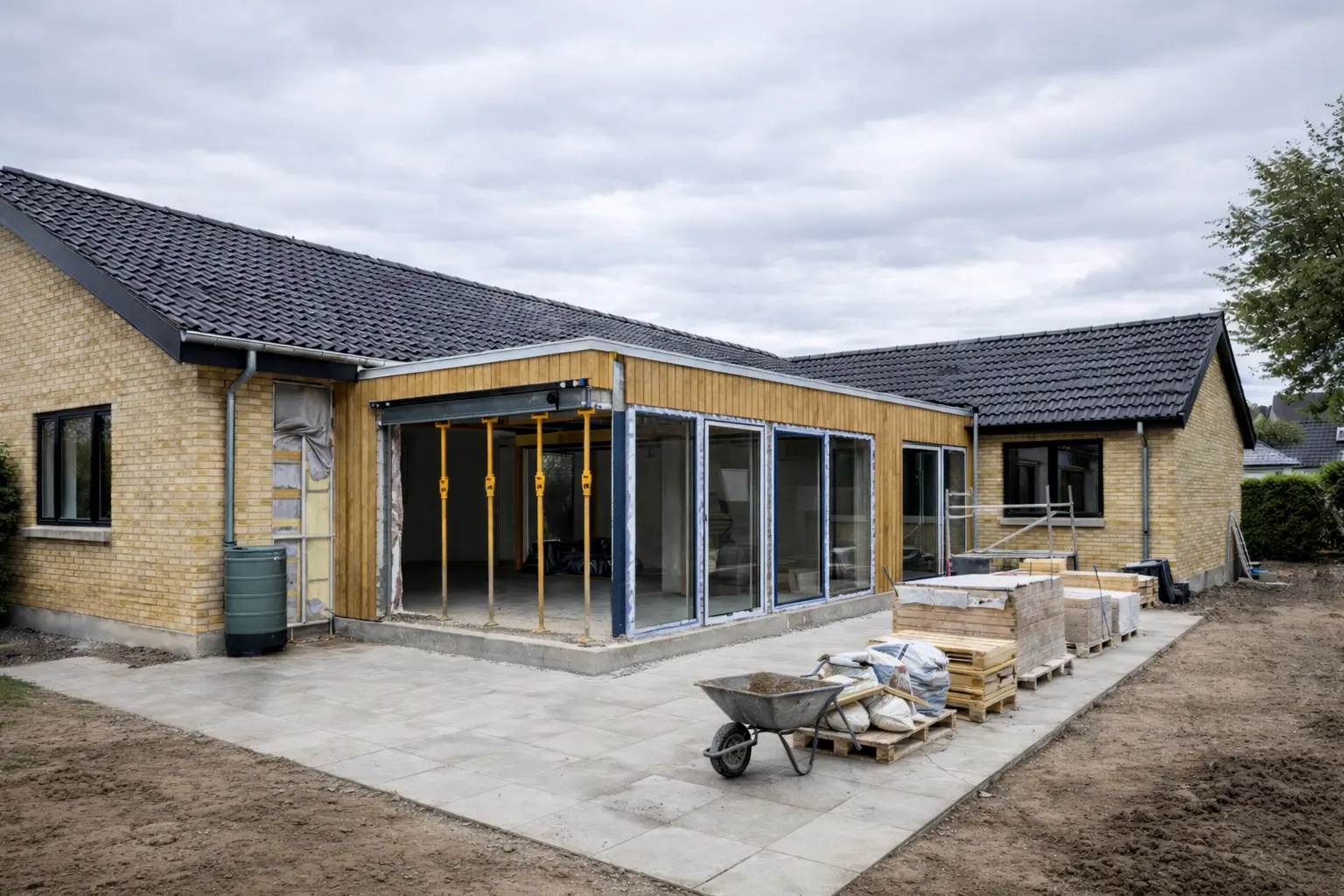 Dansk murstensvilla med stor tilbygning i thermowood under opførelse og store glaspartier.